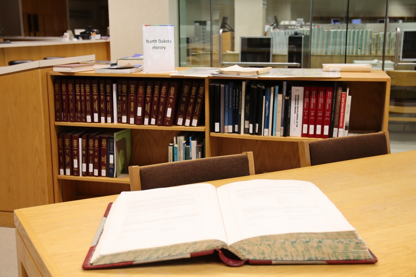 picture is of the SHSND archives reading room and shows an open ledger in the library with bookshelves. 